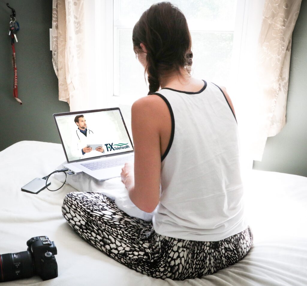 A woman using her laptop to have an online doctor appointment on her bed at home
